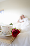 Photo: Mature couple sitting upright in bed, focus on breakfast tray with two coffee cups and single red rose in foreground Mature couple sitting upright in bed, focus on breakfast tray with two coffee cups and single red rose in foreground