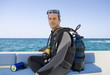 A man sitting on a boat preparing to go scuba diving