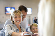 Photo: Family standing at airport check-in desk, woman handing passports to check-in attendant, smiling (differential focus) Family standing at airport check-in desk, woman handing passports to check-in attendant, smiling (differential focus)