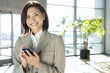 Photo: Businesswoman standing in airport, using personal electronic organiser, smiling, portrait Businesswoman standing in airport, using personal electronic organiser, smiling, portrait