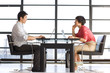 Photo: Young couple sitting oppposite each other with laptops on dining table by window, side view Young couple sitting oppposite each other with laptops on dining table by window, side view