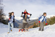 Photo: Boy pulling sled in snow field in front of parents and sister, mountain range in background Boy pulling sled in snow field in front of parents and sister, mountain range in background