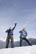 Photo: Two young men catching snow falling from sky, laughing, mountain range in background Two young men catching snow falling from sky, laughing, mountain range in background