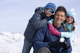 Photo: Son and daughter (6-8) embracing father in snow field, smiling, portrait, mountain range in background Son and daughter (6-8) embracing father in snow field, smiling, portrait, mountain range in background
