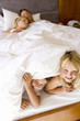 Photo: Couple with son and daughter (6-8) lying in bed, children smiling in foreground, elevated view Couple with son and daughter (6-8) lying in bed, children smiling in foreground, elevated view