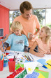 Photo: Father standing by son and daughter(6-8) sitting at art and crafts table, smiling at daughter Father standing by son and daughter(6-8) sitting at art and crafts table, smiling at daughter
