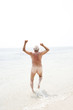 Naked senior man running into the sea