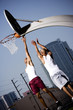 Foto: Two Young African American man jumping with a basketball on an urban basketball court Two Young African American man jumping with a basketball on an urban basketball court