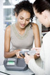 Woman keying pin number into credit card machine at the till