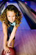 Girl in a bowling alley holding a red bowling ball