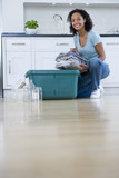 Photo: Young woman putting newspaper bundle into recycle bin by glass jars and tin cans, smiling, portrait, ground view Young woman putting newspaper bundle into recycle bin by glass jars and tin cans, smiling, portrait, ground view
