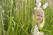 Girl (2-4) in bunny rabbit headband hiding in long grass, side view