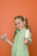 Girl (9-11) with light bulbs by orange wall, smiling, portrait