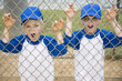 two boys roaring like lions through fence at baseball pitch