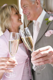 Photo: Senior bride and groom toasting with champagne flutes, close-up of glasses, low angle view Senior bride and groom toasting with champagne flutes, close-up of glasses, low angle view