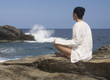 A woman meditating by the sea