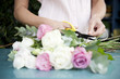 Woman's hands tying together a bouquet of pink and white roses