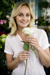 Woman florist in her shop, holding a white rose