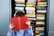 little boy hiding behind a book