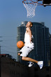 Foto: Young African American man jumping with a basketball on an urban basketball court Young African American man jumping with a basketball on an urban basketball court
