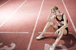 Photo: Portrait of a female athlete resting and sitting on the running track Portrait of a female athlete resting and sitting on the running track