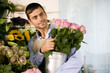 Male florist in his shop, holding a pot of pink roses