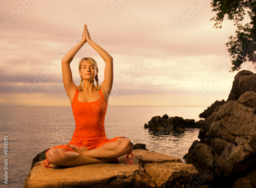 Beautiful young woman doing yoga exercise outdoors