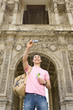 Man taking photograph of himself by archway, smiling, low angle view