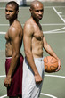 Two Young African American standing back to back on an urban basketball court