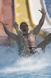A man coming down a slide in a waterpark