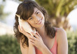 A woman holding a shell to her ear