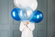 boy hiding behind a bunch of balloons