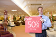 Salesman with 'sale' sign in furniture shop, smiling, portrait