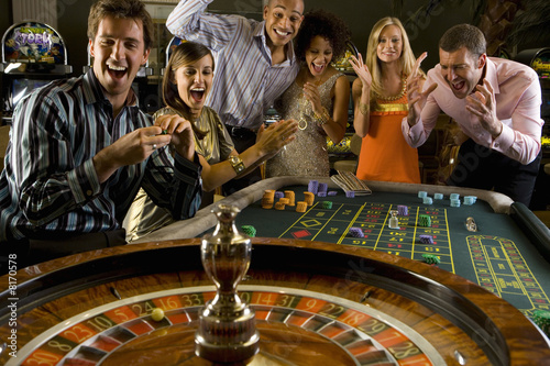 Men and women gambling at roulette table in casino, smiling, elevated view