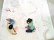 Photo: Brother and sister (6-10) drawing on large piece of paper on floor, elevated view Brother and sister (6-10) drawing on large piece of paper on floor, elevated view