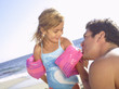Man blowing up daughter's (3-5) inflatable armbands on beach (tilt)