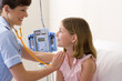 Doctor using stethoscope on girl (10-12), smiling, side view