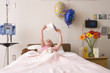 Girl (5-7) reading card in hospital bed