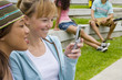 Teenage girls (15-17) using mobile phone outdoors, smiling
