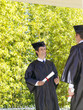 Graduates smiling at each other outdoors