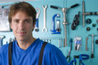 Man by tools hanging on wall, smiling, portrait