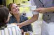 Waiter serving coffee to young couple at table outdoors