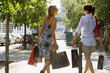 Photo: Two woman walking on the street carrying shopping bags. Two woman walking on the street carrying shopping bags.