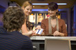 Women buying movie tickets at the box office.