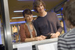 A couple buying movie tickets at the box office.