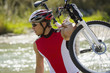 A man carrying his bike across a stream.
