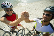Two male cyclists shake hands.