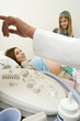 Pregnant woman having ultrasound scan with daughter (9-11), consultant pointing