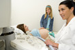 Girl (9-11) with hand on pregnant mother's stomach, having ultrasound scan