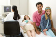 Pregnant woman having ultrasound scan with husband and daughter (9-11), smiling, portrait